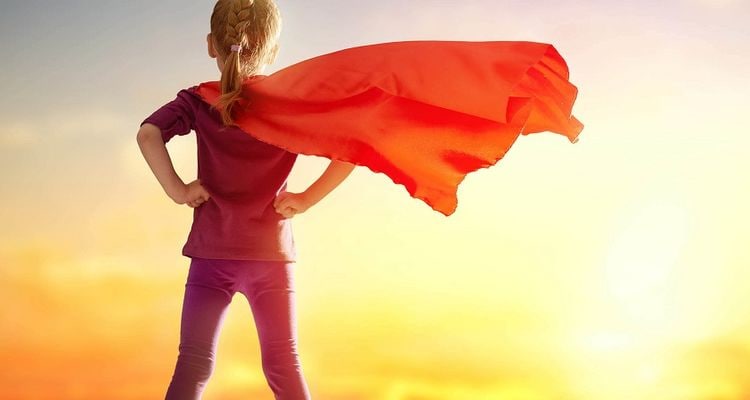 a woman in a red cape stands on a hill